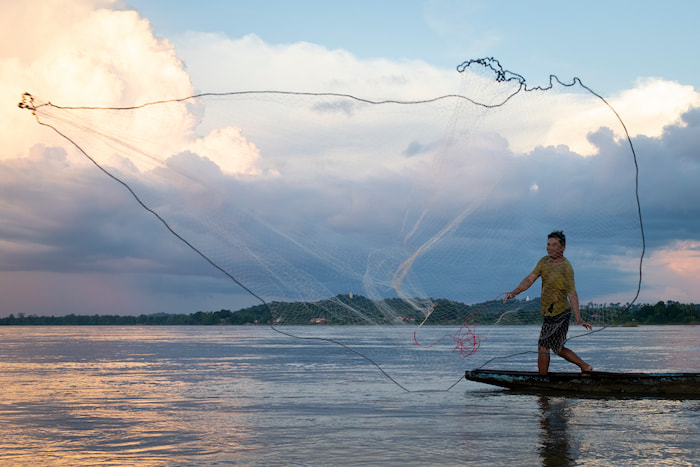 A fisher casting a net during sunset near Na Village, Kong Island, Siphandone (4000 islands), Lao PDR © Emanuela Colombo / WWF-Laos fisherman WWF livinf planet report 2024