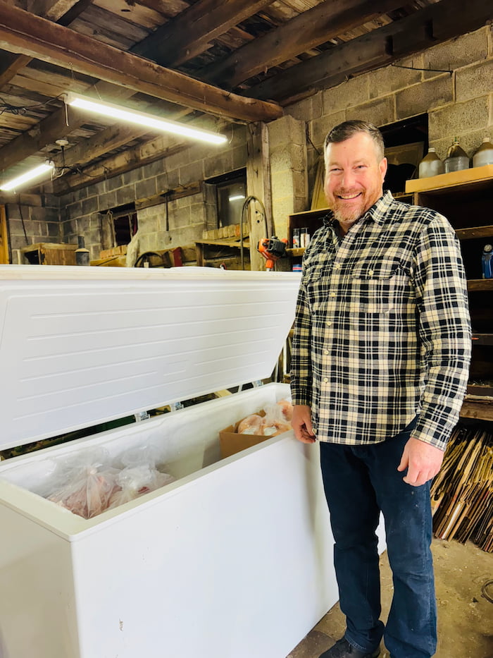 A farmer inspecting cuts of meat in the deepfreeze, showcasing the high-quality, sustainably-raised products from a regenerative farm.
