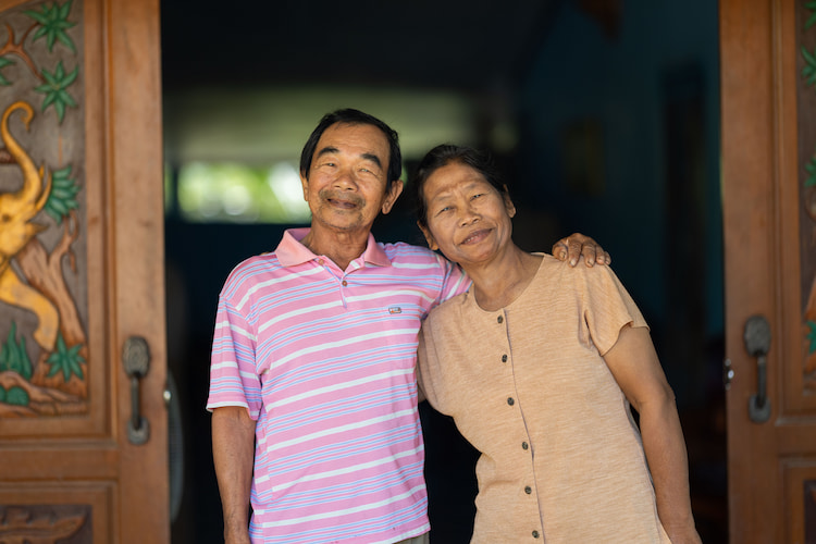 Sa-ard Ngernyouang and his wife, Roengrom Aiamsa-ard, smile outside of their homestay. 